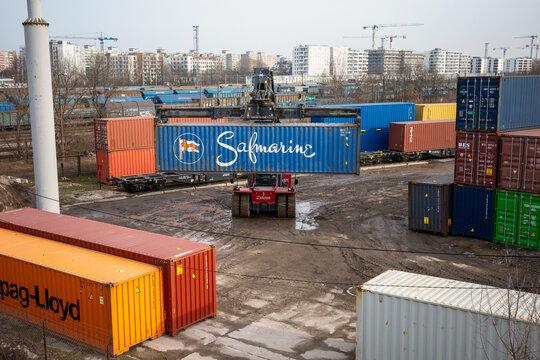 Warsaw, Poland - February 27, 2026: A red reach stacker lifts a blue Safmarine cargo container.