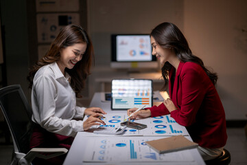 Fototapeta premium Businesswomen analyzing financial data in office at night