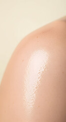 Fototapeta premium Close up of a person's shoulder with glistening skin reflecting light, highlighting texture and healthy glow, isolated on a soft neutral background