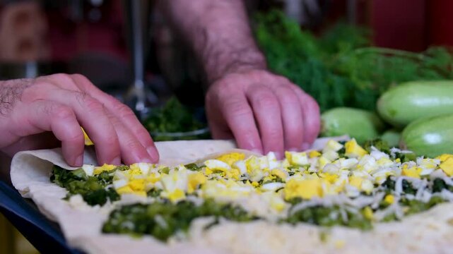 Making pita bread with cheese, spinach, and eggs. Men's hands wrap vegetables in pita bread.
