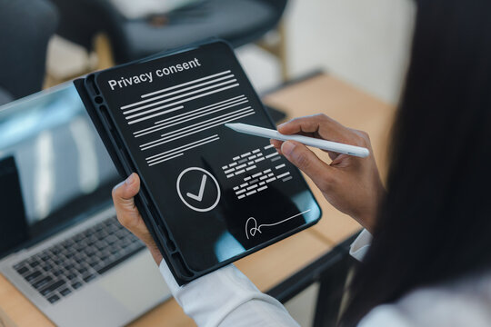 Close up of a businesswoman using a stylus pen to sign a digital privacy consent form on a tablet screen, ensuring data protection and legal compliance in a modern office.