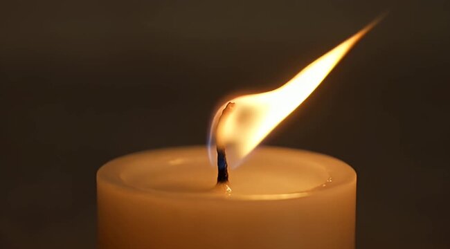 A glowing candle flame illuminating a dark background with soft diffused light