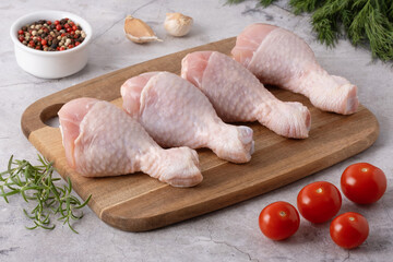 Fresh chicken drumsticks and vegetables on a cutting board in a kitchen setting ready for cooking