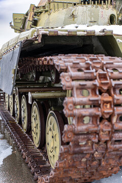 View of a rusty, weathered tank's tracks and wheels, a gritty monument against a cold backdrop, standing silent in Kyiv, Kyiv, Ukraine.