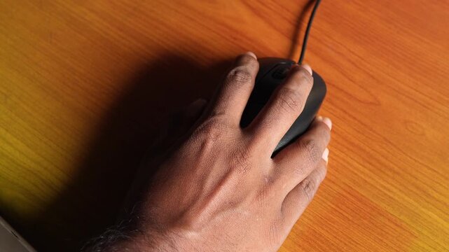 Hand using computer mouse on wooden desk