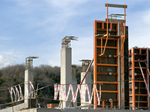 View of concrete pillars rising against a backdrop of blue sky and distant trees, a construction scene in Sariyer, Istanbul, Turkey.