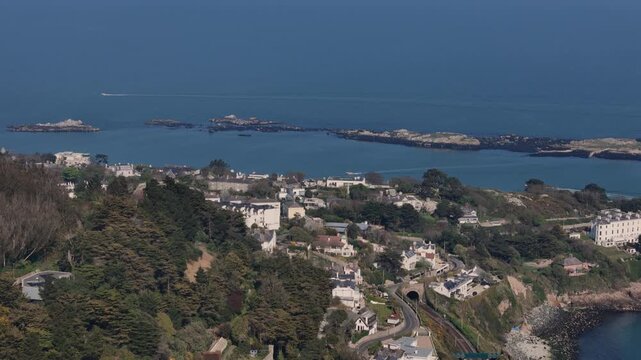 Drone footage capturing Dalkey coastline in Dublin, with waves crashing below and cliffs rising beside the tracks