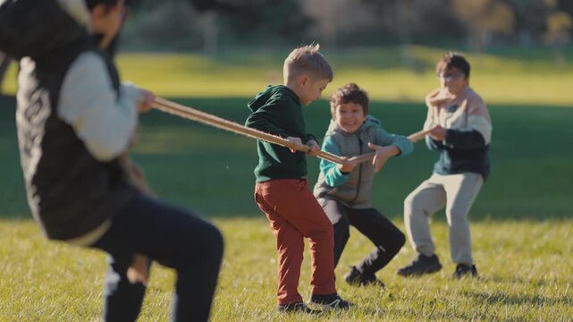 Group of children playing tug of war in sunny park