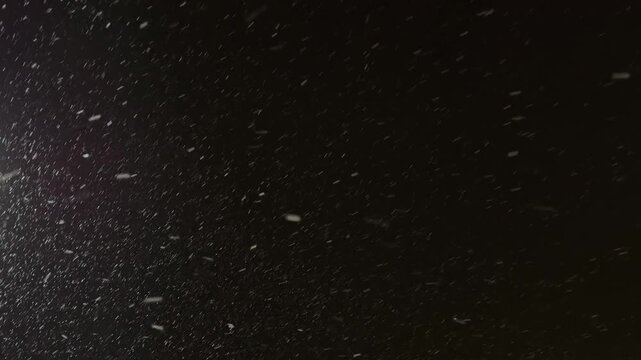 Street light illuminating falling snow during snowstorm at night. Realistic falling snow effect against a dark night sky, ideal for compositing winter scenes, creating a serene and magical atmosphere.