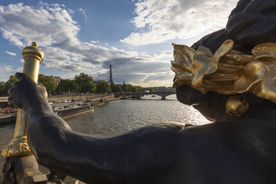 view of the Seine River flowing beneath the Pont Alexandre III bridge towards the Eiffel Tower, Paris, France.