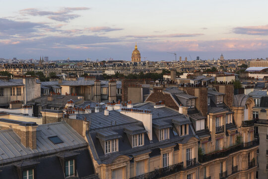 View of rooftops bathed in the soft glow of the setting sun, a golden dome punctuating the Parisian skyline in the tranquil evening, Paris, Ile-de-France, France.