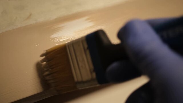 Picture restorer painting a glass frame.