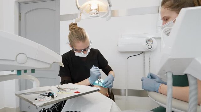 Dentist and nurse remove latex rubber dam from patient mouth finishing dental treatment. Stomatology teamwork during oral cavity therapy completion using professional medical equipment