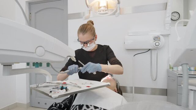 Professional female dentist changes rotary polishing attachment in modern push button contra angle handpiece. Dental equipment preparation and quick bur release mechanism for tooth treatment