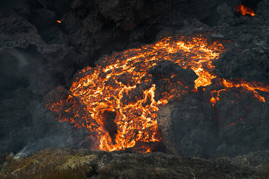 View of molten lava flowing like a river of fire through the dark, volcanic landscape, a stark contrast of destruction and creation, Grindavik, Iceland.