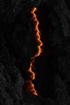 View of fiery molten lava snakes through the dark, jagged volcanic rock, a visceral display of Iceland's raw geothermal power, Grindavik, Iceland.
