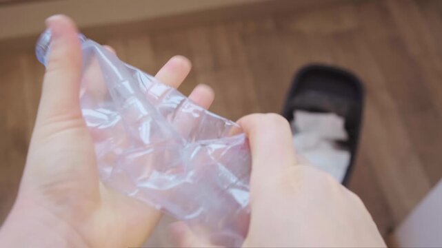 Close up of hands crushing plastic bottle and placing it in trash bin daily disposal waste sorting and caring for environment