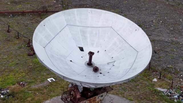 Cloudy day over the Arctic coast and the historic Orbita space communications station near Lavrentiya, Chukotka. Large parabolic dish stands on a circular base, remote tundra landscape adds appeal