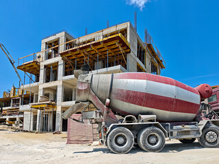 Naklejka premium Large concrete mixer truck on a construction site. Concept of real estate, architecture, and urban development.