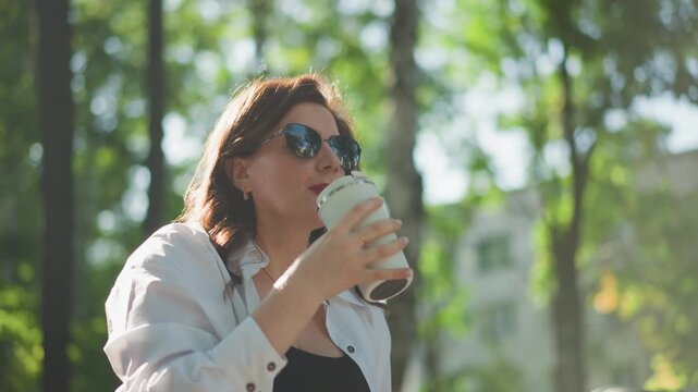 Women happily enjoy hot beverages. Women delight in drinking warm beverages while taking outdoor strolls. Women happily indulge in hot drinks during outdoor walks with friends oring walk