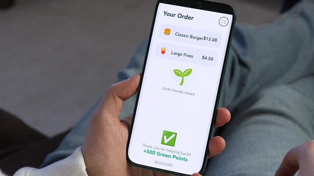 Making a conscious choice: ordering fast food without plastic waste. Close-up of hands using a sustainable delivery app interface. Real-world solution for zero waste lifestyle.