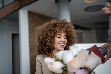 Woman receiving surprise flowers and gift at workplace