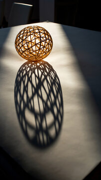 Decorative spherical object casting intricate shadow on surface.