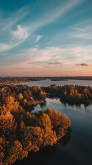 Obraz premium Aerial view of a river with autumn-colored trees and a sunset sky.