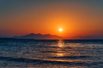 Fototapeta premium Golden sunset over the tranquil sea with mountains in the distance