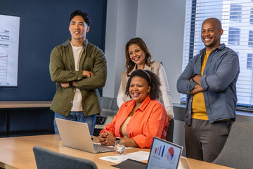 Diverse coworkers watching African American woman leading meeting with laptop, charts in office