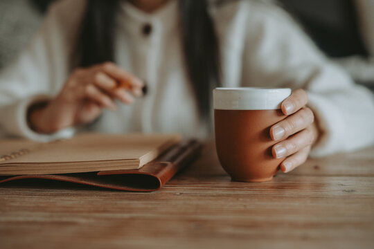 Femme &eacute;crivant dans un carnet en cuir avec une tasse de caf&eacute;, concept de planification et de bien-&ecirc;tre