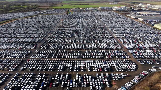 Aerial view of a car storage facility with rows of neatly arranged vehicles stretching out, creating a mesmerizing pattern of shapes and shadows, Grimsby, United Kingdom.