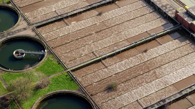 Aerial view of Severn Trent Water treatment plant, with circular tanks and rectangular basins creating an intricate pattern of textures and tones, Coleshill, United Kingdom.