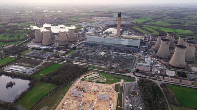 Aerial view of Drax Power Station, a tapestry of industrial prowess amidst verdant fields, with cooling towers releasing plumes into the sky, Selby, United Kingdom.