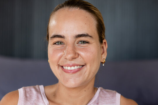 Female posing facing camera in studio with sleeveless pink top and pearl hoop earrings