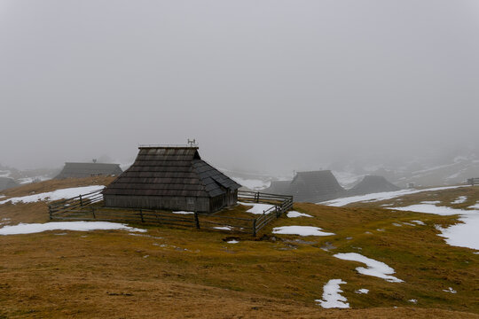 Cabin in snowy mountain peak landscape with fog and clouds. Background for winter tourism and mountain travel