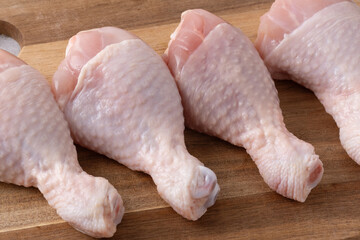 Raw chicken drumsticks ready for cooking on a wooden cutting board in a kitchen setting