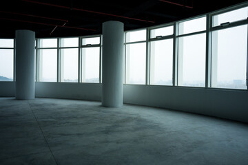 Naklejka premium Empty modern office space with floor-to-ceiling windows concrete columns and industrial interior design