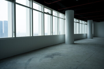 Naklejka premium Empty modern office space with floor-to-ceiling windows and concrete columns