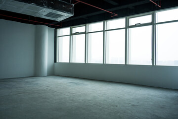 Naklejka premium Empty unfinished office space with large floor-to-ceiling windows and natural light illumination