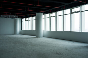 Spacious industrial-style office space with unfinished concrete interior and large windows