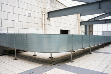 Naklejka premium Metal ventilation duct system installed on industrial building rooftop with structural supports and tiled platform