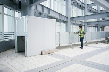 Worker inspecting equipment enclosure inside industrial factory building