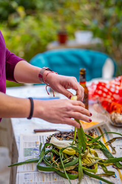 Close-up of hands peeling traditional Catalan grilled cal&ccedil;ots on newspaper during an outdoor cal&ccedil;otada.