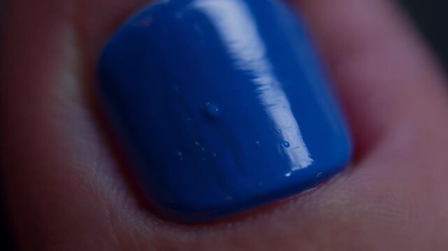 Bright blue nail polish application on fingernail close up at home in soft light during afternoon hours