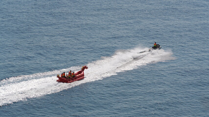 Water tubing. A jet ski pulls an inflatable structure with passengers. An extreme sea ride.