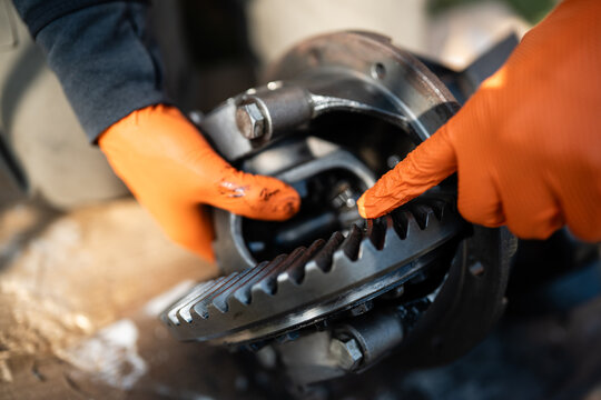 Mechanic pointing a car differential gear during repair