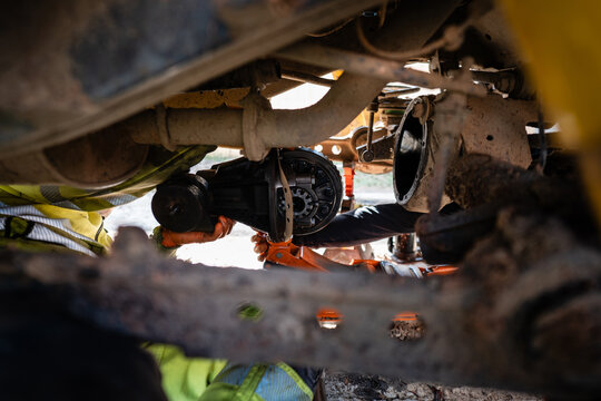 Mechanic repairing vehicle differential and axle undercarriage
