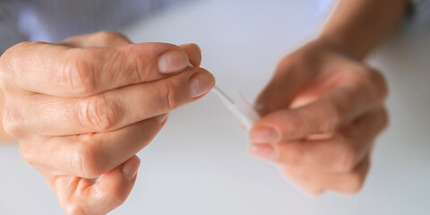 At-home rapid test kit, hands collecting nasal swab sample into tube, self testing, medical diagnostics, infection screening, telehealth concept, copy space. © shintartanya