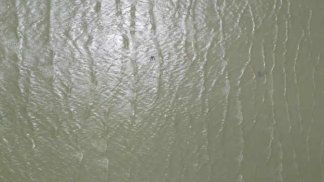 썰물로 드러난 광활한 갯벌에서 물을 헤치며 나아가는 사람의 역동적인 모습과 평온한 자연 풍경
